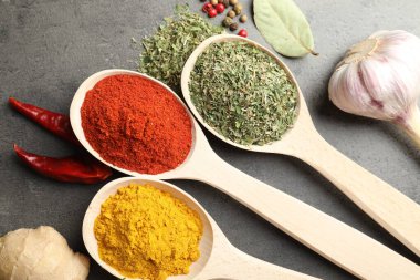 Gri masadaki kaşıklardaki farklı baharatlar düzdü.