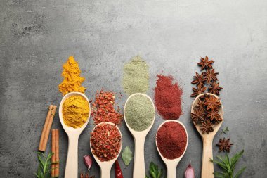 Gri masadaki kaşıklarda bir sürü farklı baharat var. Metin için boşluk