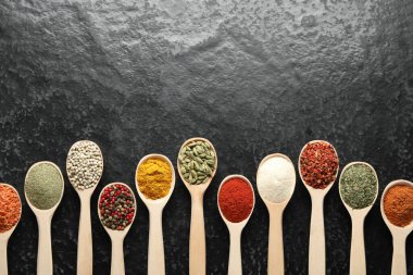 Siyah masadaki kaşıklarda bir sürü farklı baharat var. Metin için boşluk