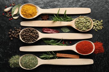 Siyah masadaki kaşıklarda bir sürü farklı baharat var.