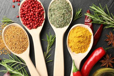 Siyah masadaki kaşıklardaki farklı aromatik baharatlar.