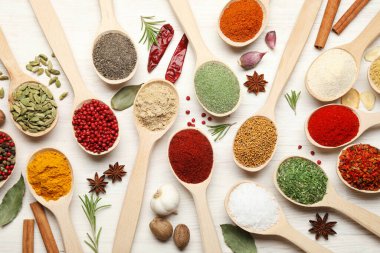 Beyaz ahşap masadaki kaşıklardaki farklı aromatik baharatlar.