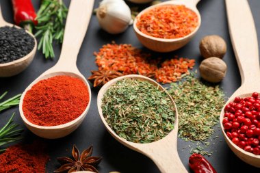 Siyah masada kaşıklardaki farklı aromatik baharatlar, yakın plan.