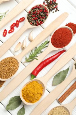 Beyaz ahşap masadaki kaşıklardaki farklı aromatik baharatlar.