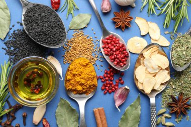 Mavi arka planda farklı aromatik baharatlar ve yağ var.