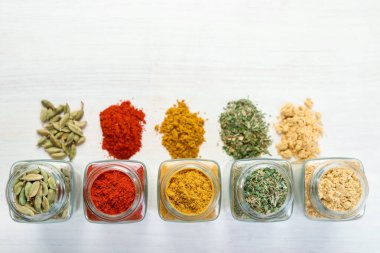 Beyaz masadaki kavanozlarda farklı aromatik baharatlar var. Metin için boşluk