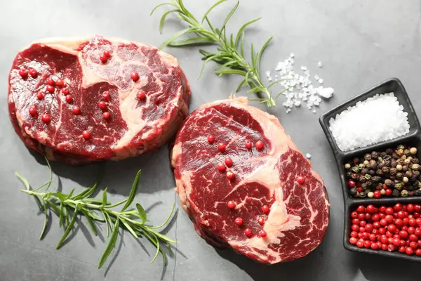 Çiğ et parçaları ve baharatlar gri dokulu masa üzerinde, düz yatıyordu.