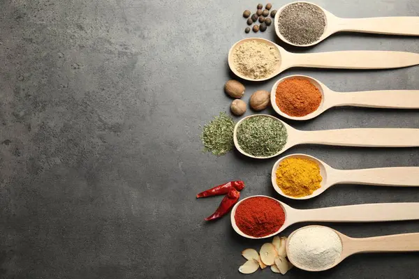 Gri masadaki kaşıklarda bir sürü farklı baharat var. Metin için boşluk