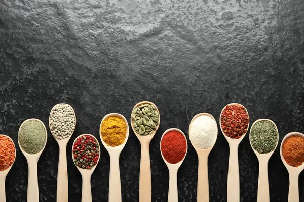 Siyah masadaki kaşıklarda bir sürü farklı baharat var. Metin için boşluk