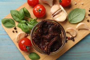 Lezzetli, kurutulmuş domatesler, taze sebzeler, fesleğen ve sarımsak mavi ahşap masa, üst manzara