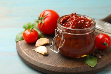 Lezzetli, kurutulmuş domatesler, taze sebzeler ve açık mavi ahşap masada biberler, yakın plan.