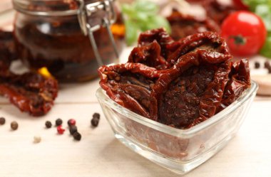 Lezzetli güneşte kurutulmuş domatesler, taze sebzeler ve ahşap masada biberler, yakın plan.