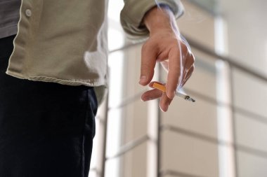 Arka planda sigara içen adam, yakın plan.