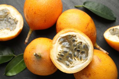 Olgun tutku meyveleri ve yeşil yapraklar siyah masanın üzerinde, düz yatıyordu.