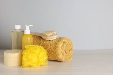 Açık ahşap masada gri arka planda farklı banyo aksesuarları, yakın plan. Metin için boşluk