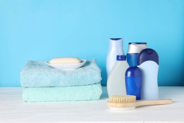 Beyaz ahşap masa üzerinde farklı banyo aksesuarları açık mavi arka plan, yakın plan