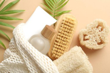 Doğal lif süngeri, kozmetik ürünleri, bej arka planda fırça ve yeşil dallar, düz uzanma