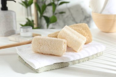 Beyaz masada farklı banyo süngeri ve havlular, yakın plan.