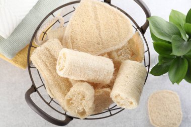 Sepette farklı lif süngerleri ve açık gri masa üzerinde havlular.