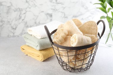 Sepette farklı lif süngerleri ve açık gri masada havlular.