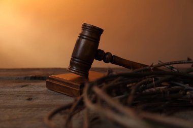 Hakimin tokmak ve dikenli tacı ahşap masa üzerinde soluk turuncu eğimli arka plan, yakın çekim