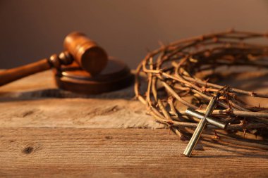 Çapraz dikenli taç ve ahşap masada yargıç tokmağı, yakın plan.