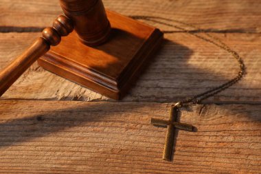 Hakimin tokmağı ve haçı tahta masada, manzaranın üstünde.