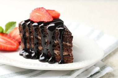 Bir parça çikolatalı kek. Masada çilek var. Yakın plan.