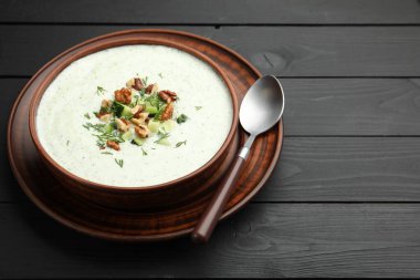 Siyah ahşap masada servis edilen dereotlu ve cevizli lezzetli salatalık çorbası, yakın plan. Metin için boşluk