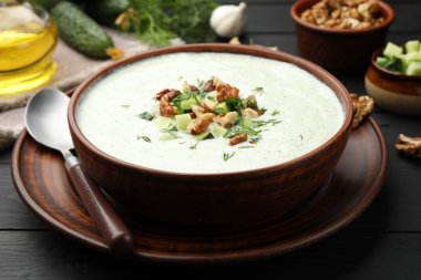 Siyah ahşap masada servis edilen dereotlu ve cevizli lezzetli salatalık çorbası.
