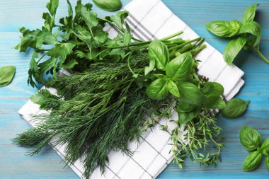 Mavi ahşap masada farklı taze otlar, düz uzanmış.