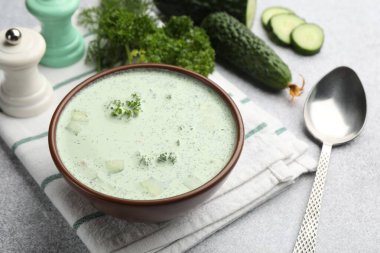 Salatalık çorbası, kaşık ve malzemeler açık gri masada, yakın plan.