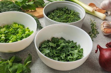 Gri masada farklı taze otlar ve baharatlar, yakın plan.