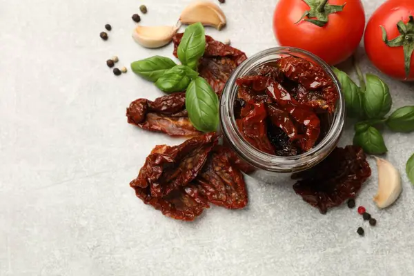 Lezzetli güneşte kurutulmuş domatesler, taze sebzeler ve baharatlar gri masada, düz yerde. Metin için boşluk