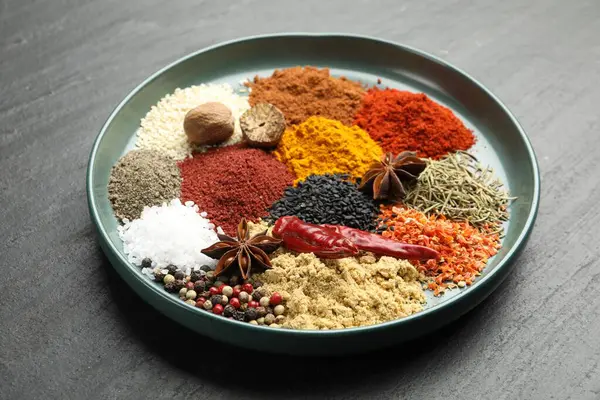 Koyu dokulu masada farklı aromatik baharatlar, yakın plan.