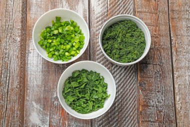 Tahta masadaki kaselerde farklı taze otlar.