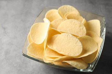 Gri masada lezzetli patates cipsleri, yakın plan.