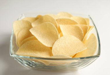 Beyaz arka planda lezzetli patates cipsi, yakın plan.