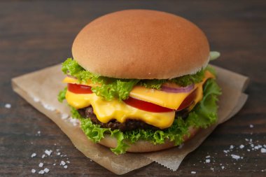 Ahşap masada marul ve domatesli leziz bir çizburger.