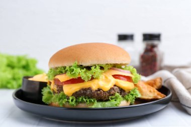 Sos ve patates dilimli leziz bir çizburger, yakın plan.