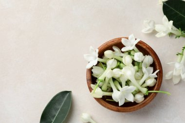 Üzerinde yasemin çiçekleri olan bir kase bej masa, düz. Metin için boşluk