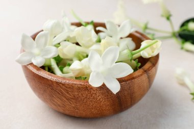 Bej masanın üzerinde yasemin çiçekleri olan kase, yakın plan.