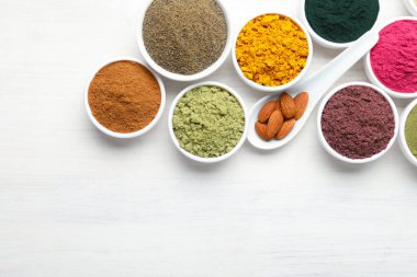 Beyaz ahşap masa üzerinde farklı süper yiyecek tozları, düz yatış. Metin için boşluk