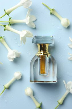 Parfüm ve yasemin çiçekleri açık mavi arka planda, düz yerde