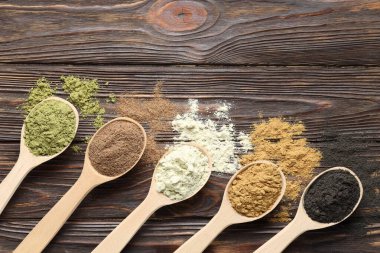 Farklı süper yiyecek tozları ve kaşıklar ahşap masada, düz yatıyordu.