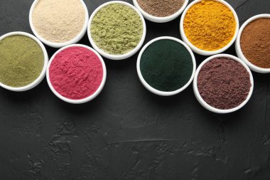 Koyu dokulu masada, düz yerde, kaselerde farklı süper yiyecek tozları var. Metin için boşluk