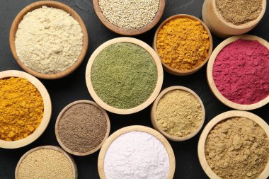 Koyu dokulu masada, düz bir zeminde, kaselerdeki farklı süper yiyecek tozları.