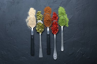 Siyah masadaki kaşıklardaki farklı süper yiyecekler.