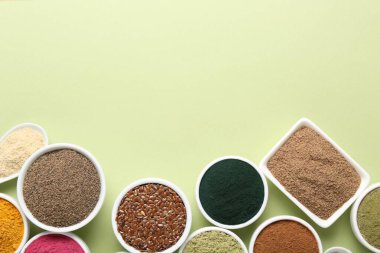 Açık yeşil arka planda, kaselerde farklı süper yiyecek tozları var. Metin için boşluk