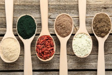 Tahta masadaki kaşıklardaki farklı süper yiyecekler.